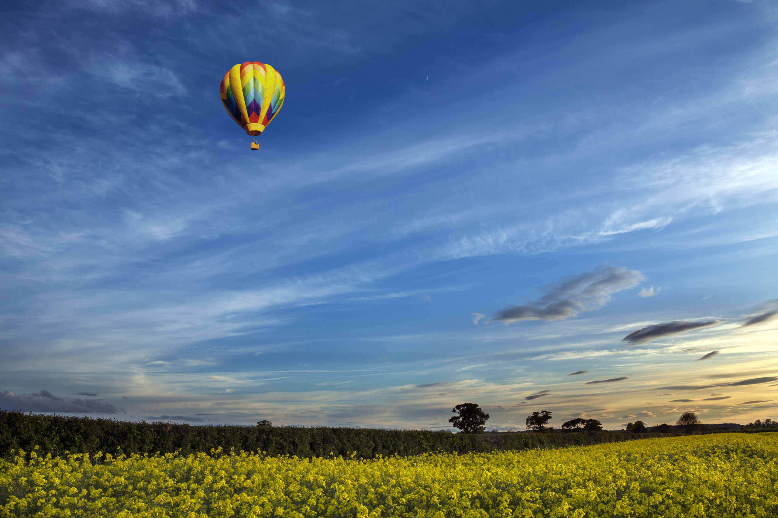 A hot air balloon drifting over the North Yorkshire countryside in the late afternoon sunshine.