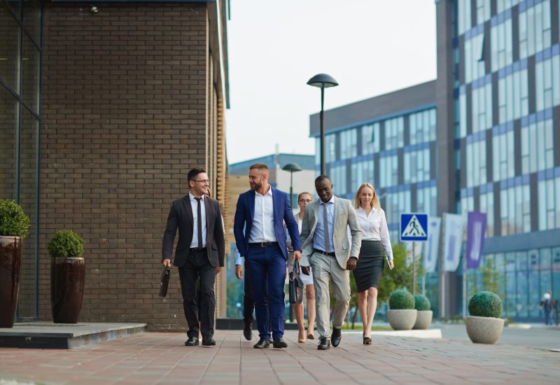 Team of co-workers moving down street and talking